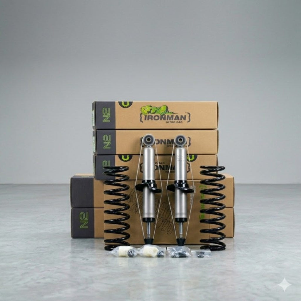 A pair of silver and black N2 shock absorbers with black coil springs, displayed in front of stacked brown Ironman brand boxes on a light gray studio background.