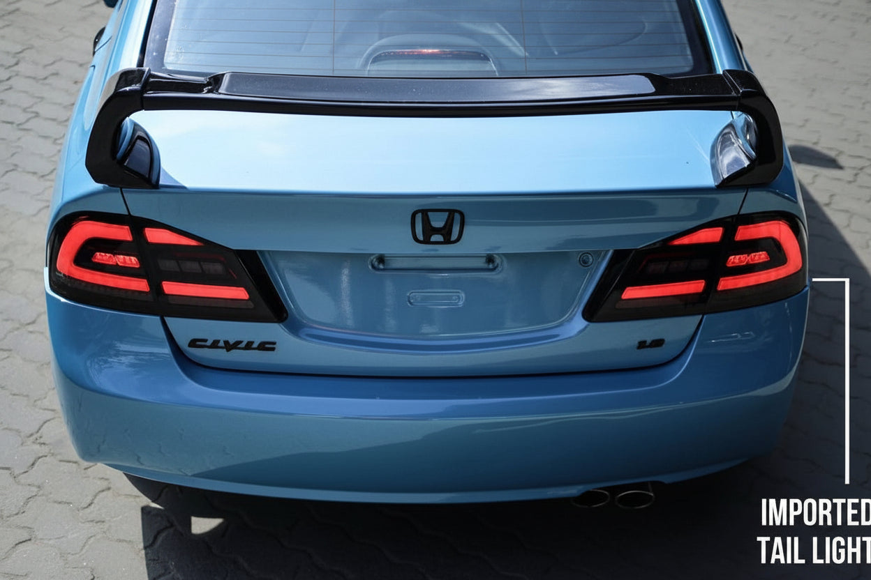 Blue car with a black rear spoiler and red taillights on a gray pavement background.