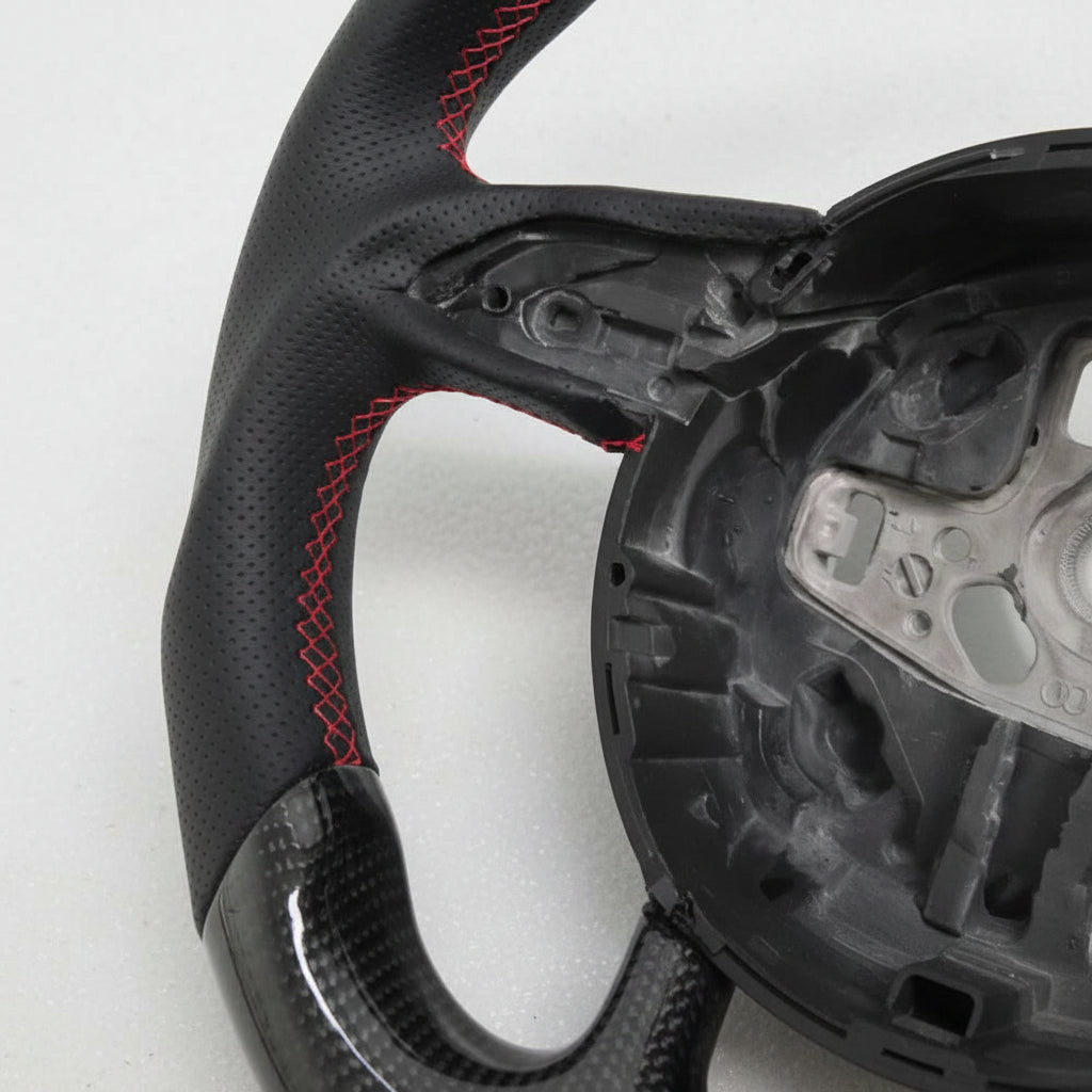 Close-up of a steering wheel with red stitching on a white background