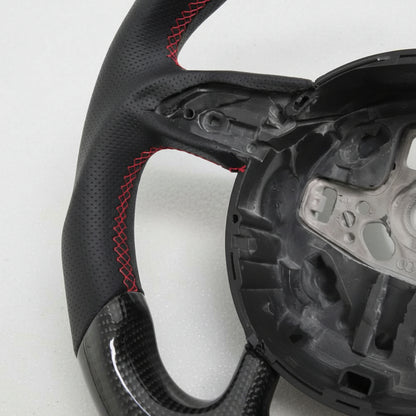 Close-up of a steering wheel with red stitching on a white background