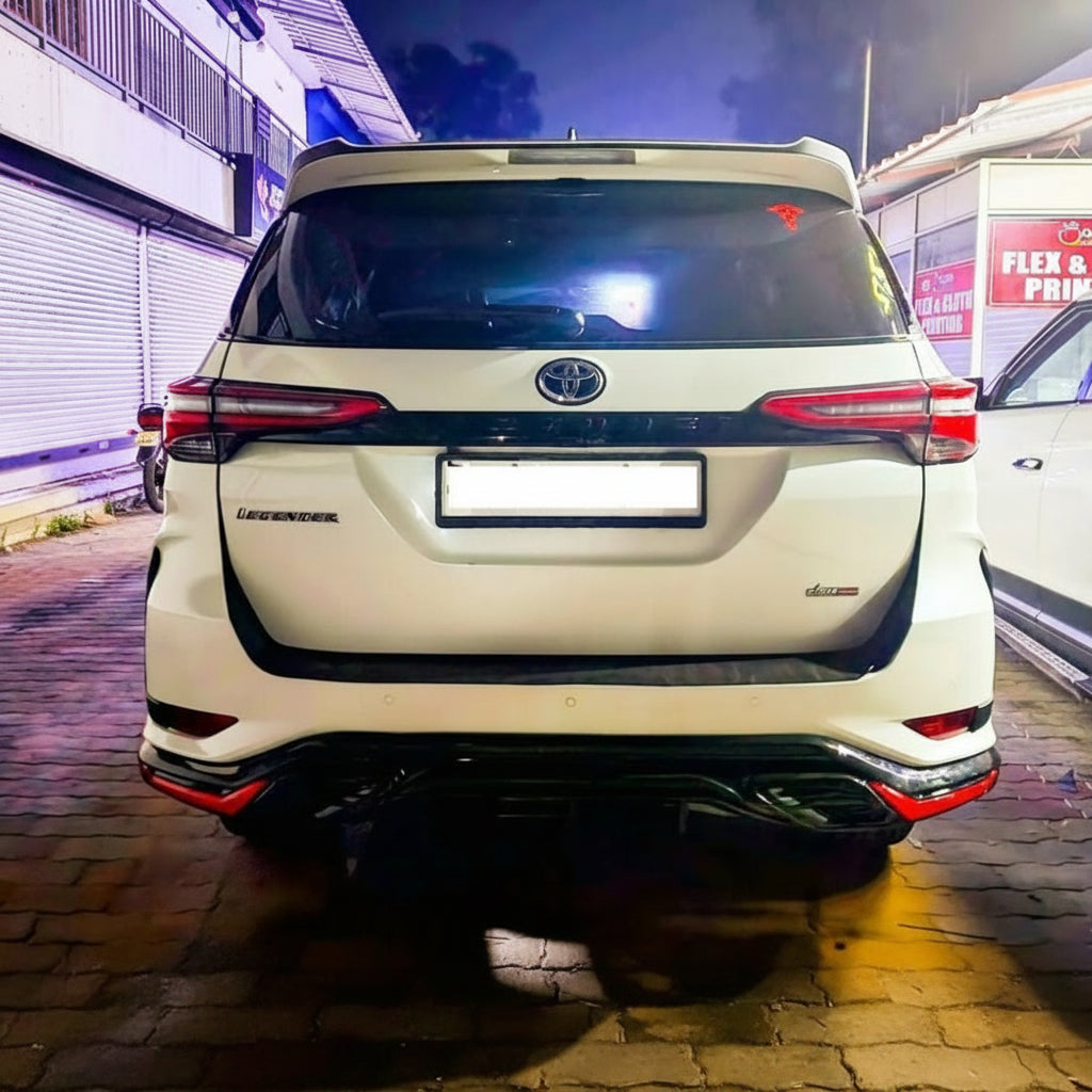 Back view of a white Toyota Fortuner SUV parked on a street at night.