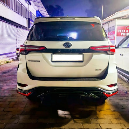 Back view of a white Toyota Fortuner SUV parked on a street at night.