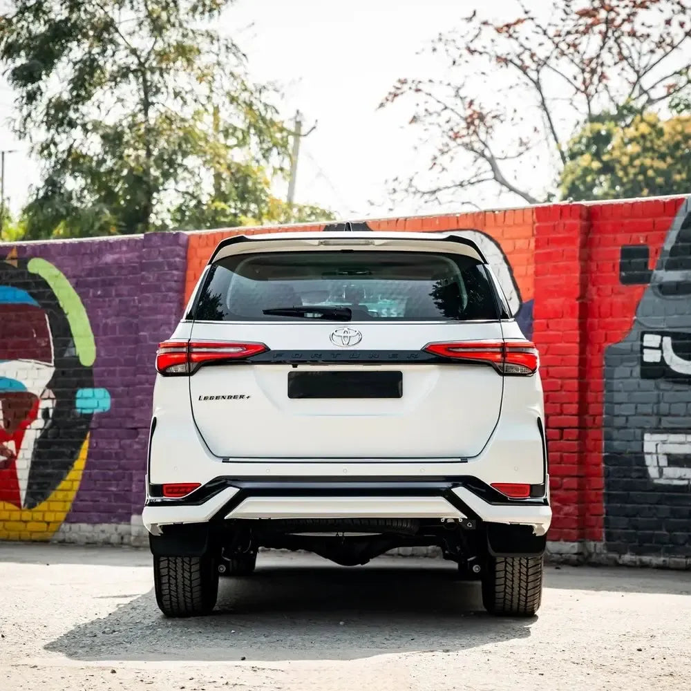 White Toyota SUV parked in front of a colorful mural.