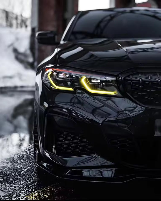 Close-up of a black car's front grille and headlight with yellow DRL with a blurred background