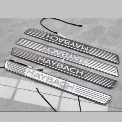 Set of Maybach branded metallic door sills on a gray surface