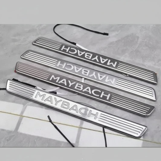 Set of Maybach branded metallic door sills on a gray surface