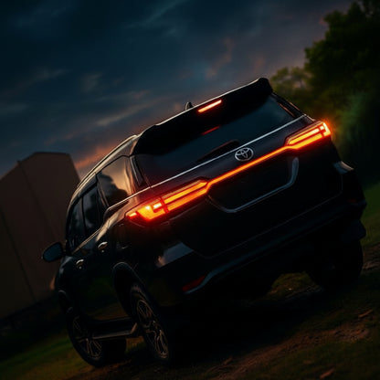 Back view of a black Toyota SUV with illuminated taillights at dusk.