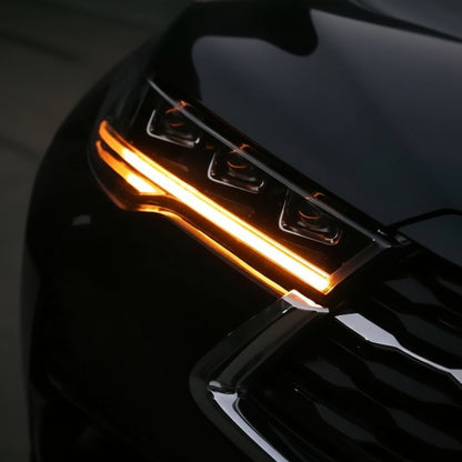 Car headlight with orange indicator light on a dark background