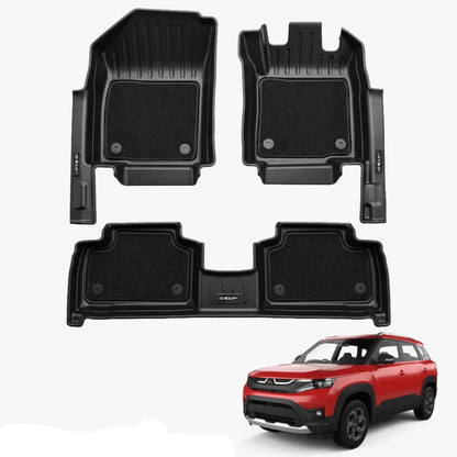 Three-piece black car floor mat set including two front footwells, two rear footwells, and a trunk liner, shown on a light grey background with a red Brezza SUV in the bottom right corner and a blue text label reading BREZZA 2022+ XLMGRIP.