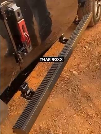 Metallic running board on a vehicle with 'THAR ROXX' branding on a dirt surface.