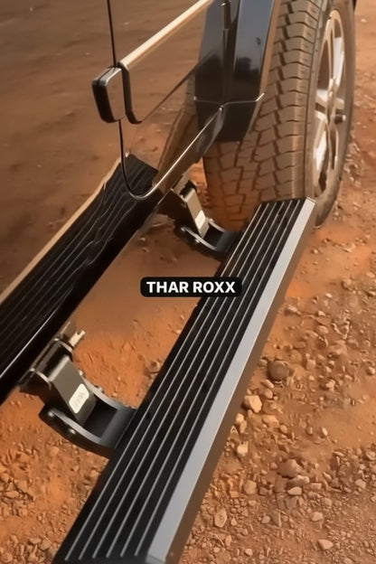 Close-up of a vehicle's step bar with 'THAR ROXX' branding on a dirt surface.