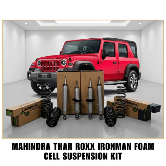 Mahindra Thar Roxx Ironman Foam Cell Suspension Kit displayed with its components, including shock absorbers, coil springs, and branded cardboard boxes, set against a red Jeep Wrangler in a white studio environment.